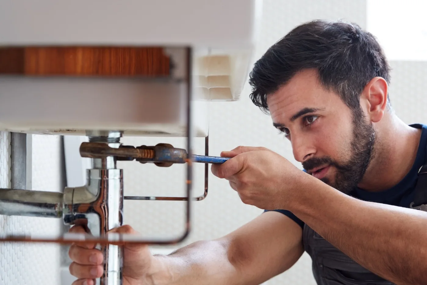 Handwerker repariert den Abfluss unter einem Waschbecken